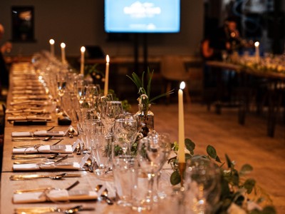 A candelit long table set with cutlery and wine glasses at a Cotswold Farm Park Supper Club event