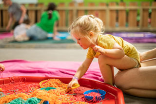 A little girl explores colourful spaghetti