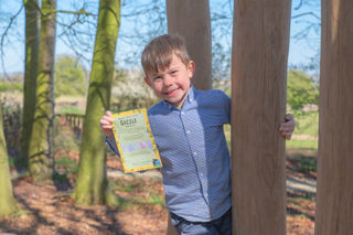 A boy standing in woodland holding an Gozzle egg hunt answer sheet at Cotswold Farm Park Easter on the Farm