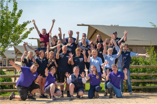 A group of Cotswold Farm Park employees cheering in the sunshine after winning a Tripadvisor award