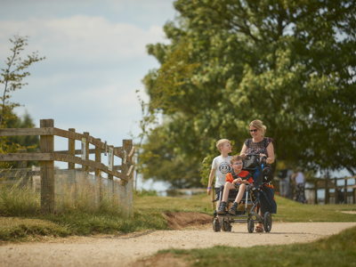 A mother pushes her son, in his chair, along our accessible pathway